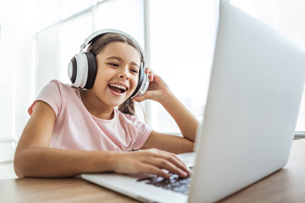the happy girl in headphones with a laptop sitting at the table